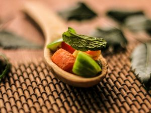 A wooden spoon filled with sliced fruit on top of a table
